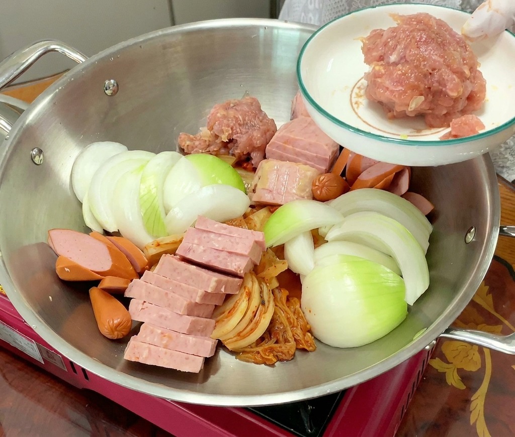 鍋の中央に、味付けされたピンク色の豚ひき肉をこんもりと盛り付けている様子。