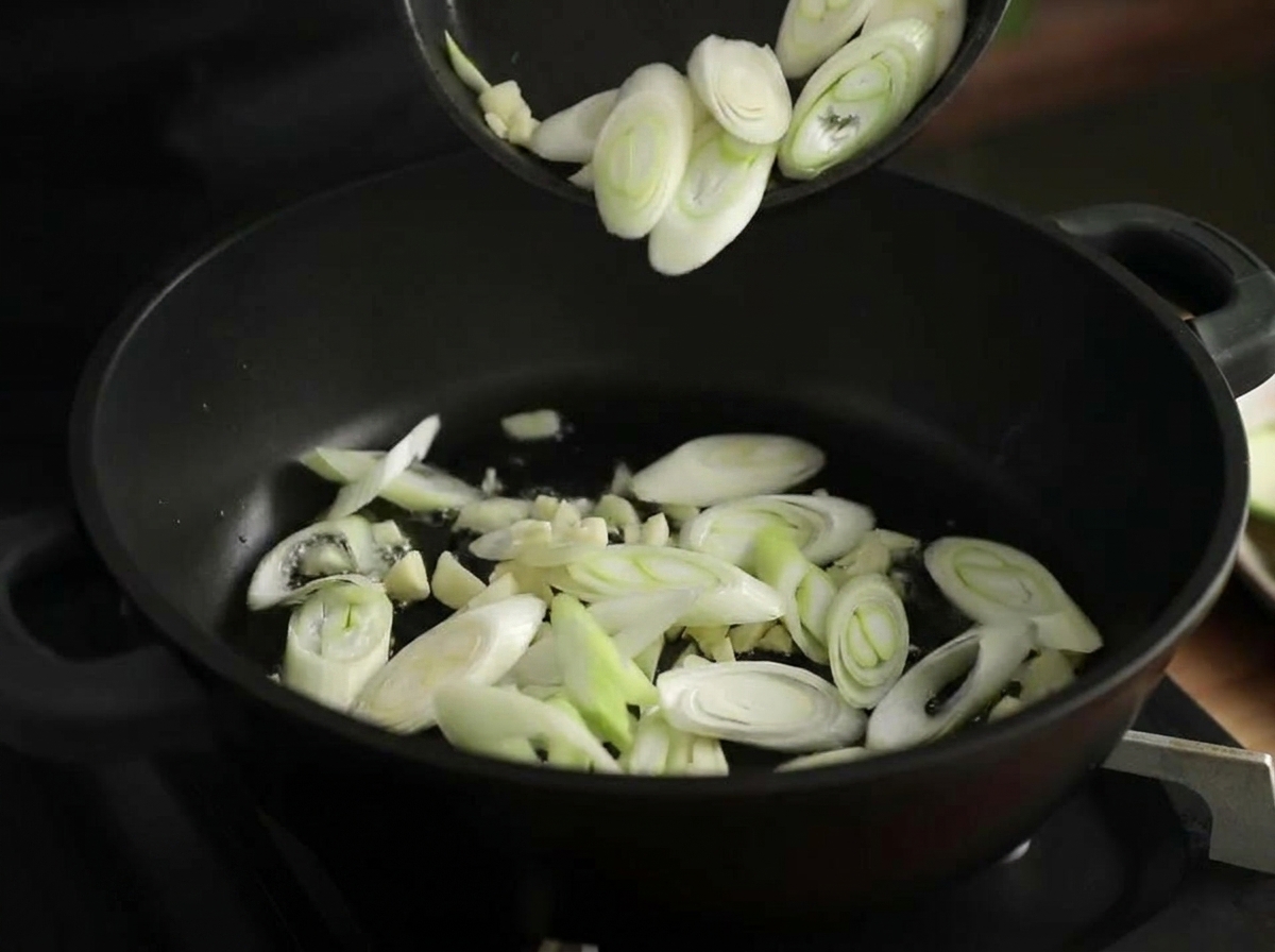 鍋で刻みにんにくと長ねぎを炒める様子