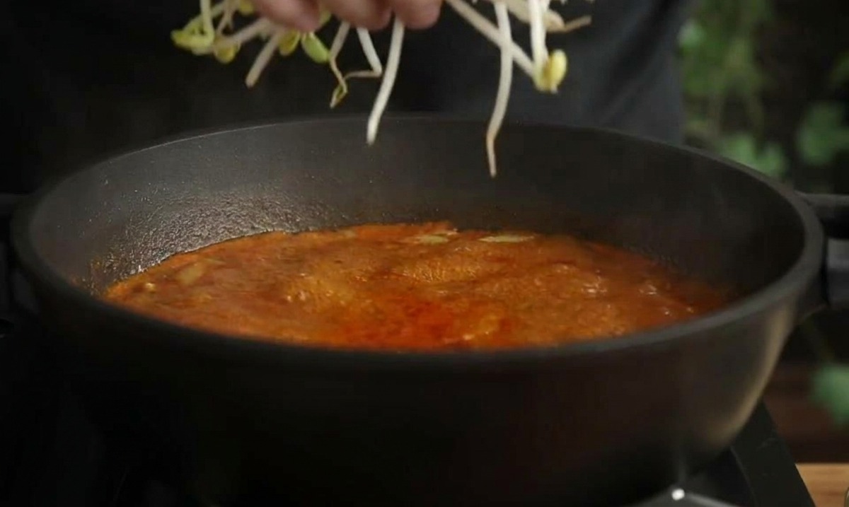 赤いスープに豆もやしを投入する様子