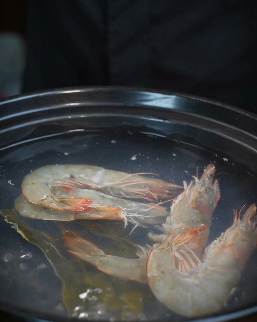 エビの入った鍋に、ボウルから新鮮なアサリを流し込んでいる様子。