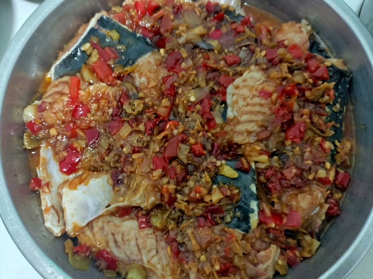 蒸し器の中で鮮やかなソースとともに蒸し上がった魚の切り身。