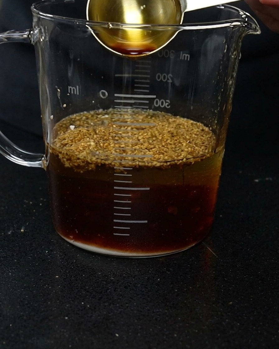 水と調味料が入った計量カップに、醤油を注ぎ入れる様子。