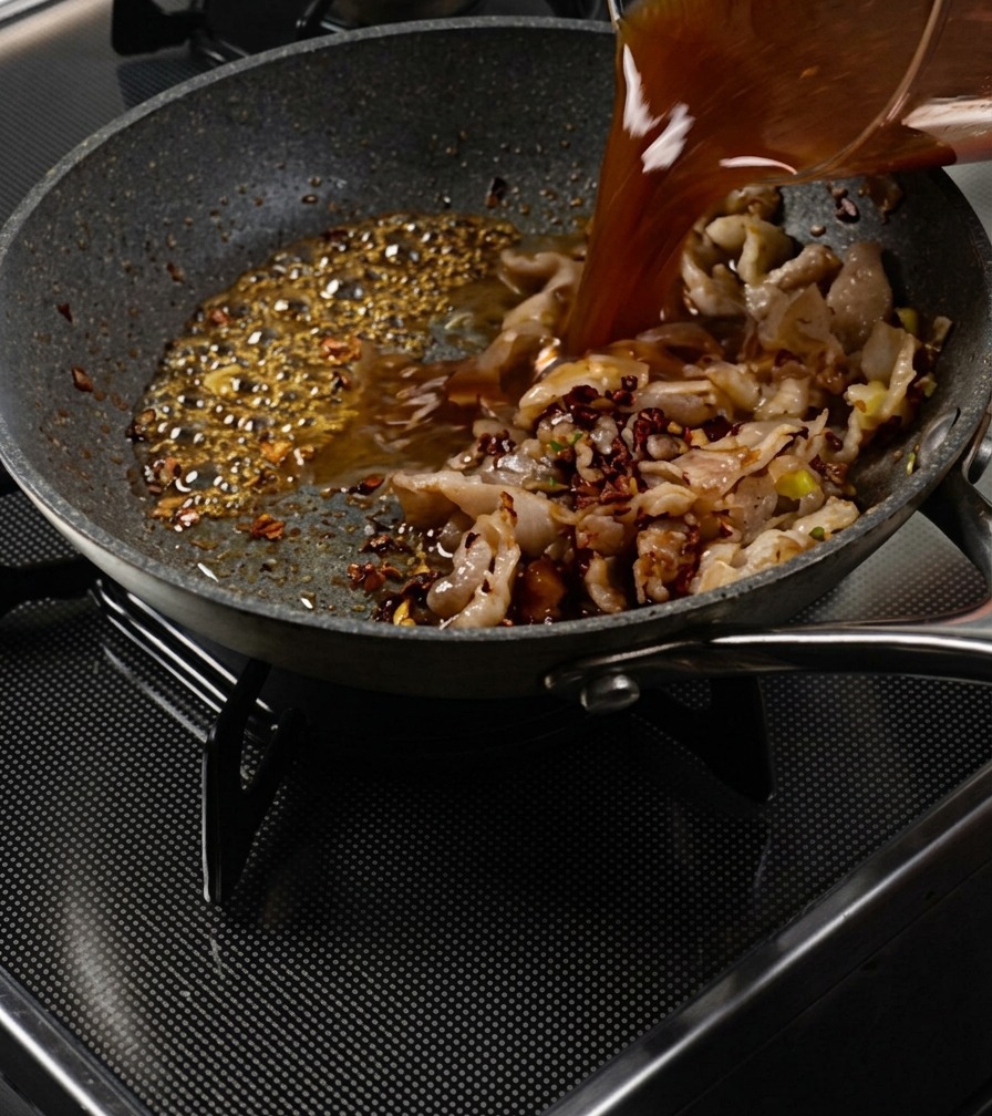 沸騰したキャラメルと具材が入ったパンに、合わせ調味料を注ぐ様子。