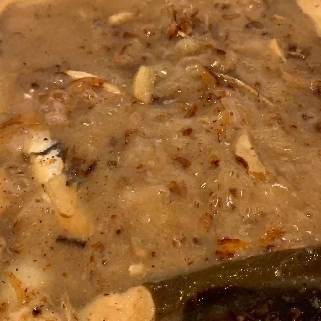 濁りのあるスープの中で、かつお節や煮干しがふつふつと煮込まれている接写。