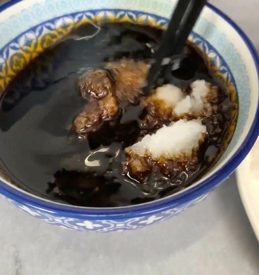 青いボウルのつゆに大根おろしを入れ、箸で混ぜ合わせている様子。