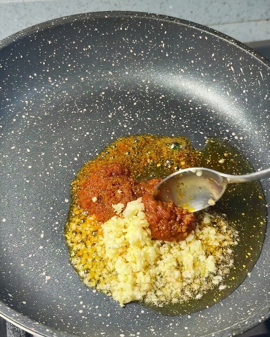 エビペーストとごま油が入ったフライパンに、刻みにんにくを加えている様子。