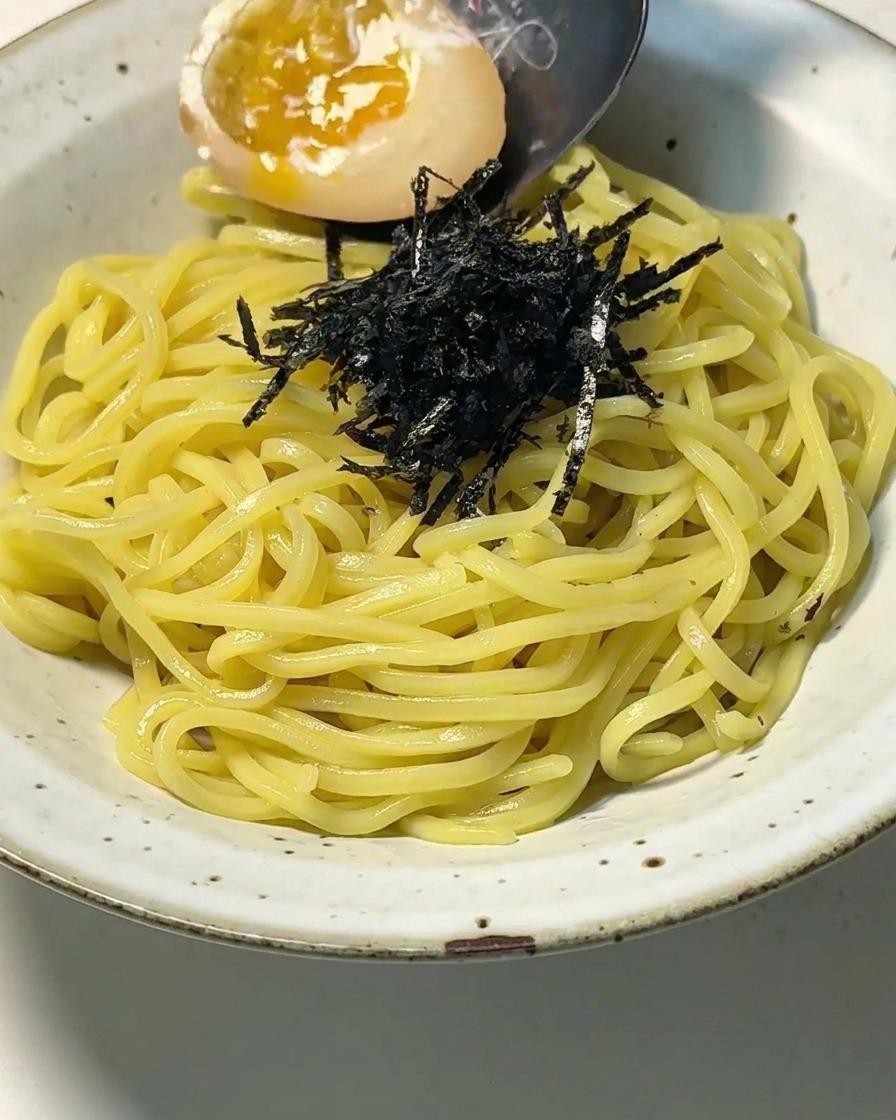 麺の隣に、とろりとした温泉卵を丁寧に配置している様子。