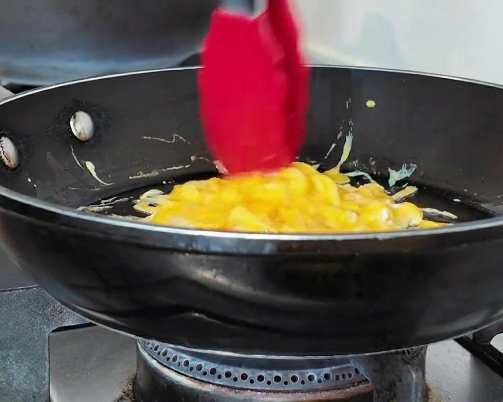 トングを使って、フライパンの中の卵を丸い形に整えている様子