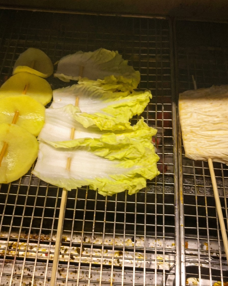 串に刺したじゃがいも、キャベツ、えのきをグリルの網に並べて焼いている様子