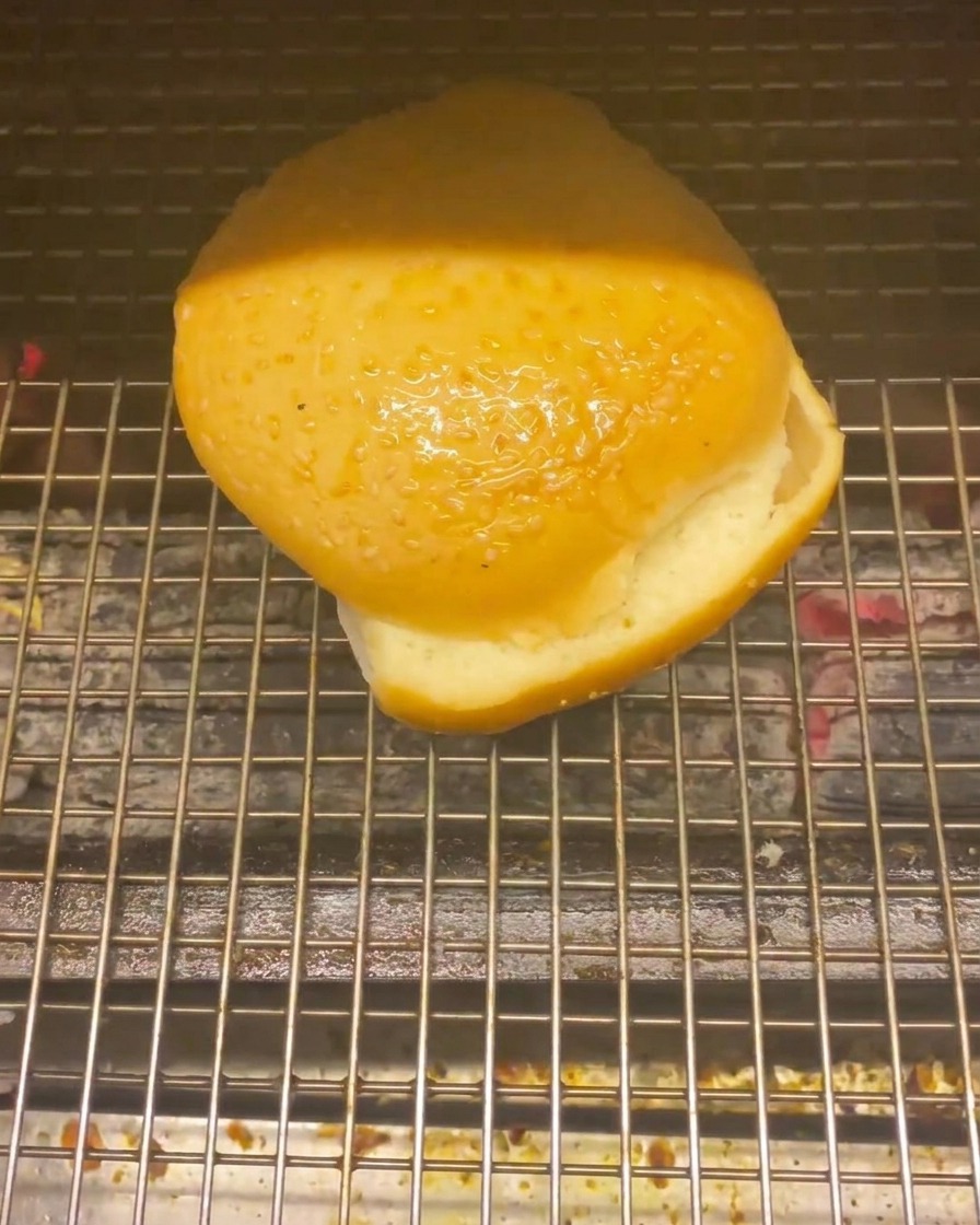 炭火の上の網でバーガーバンズを軽く焼いている様子