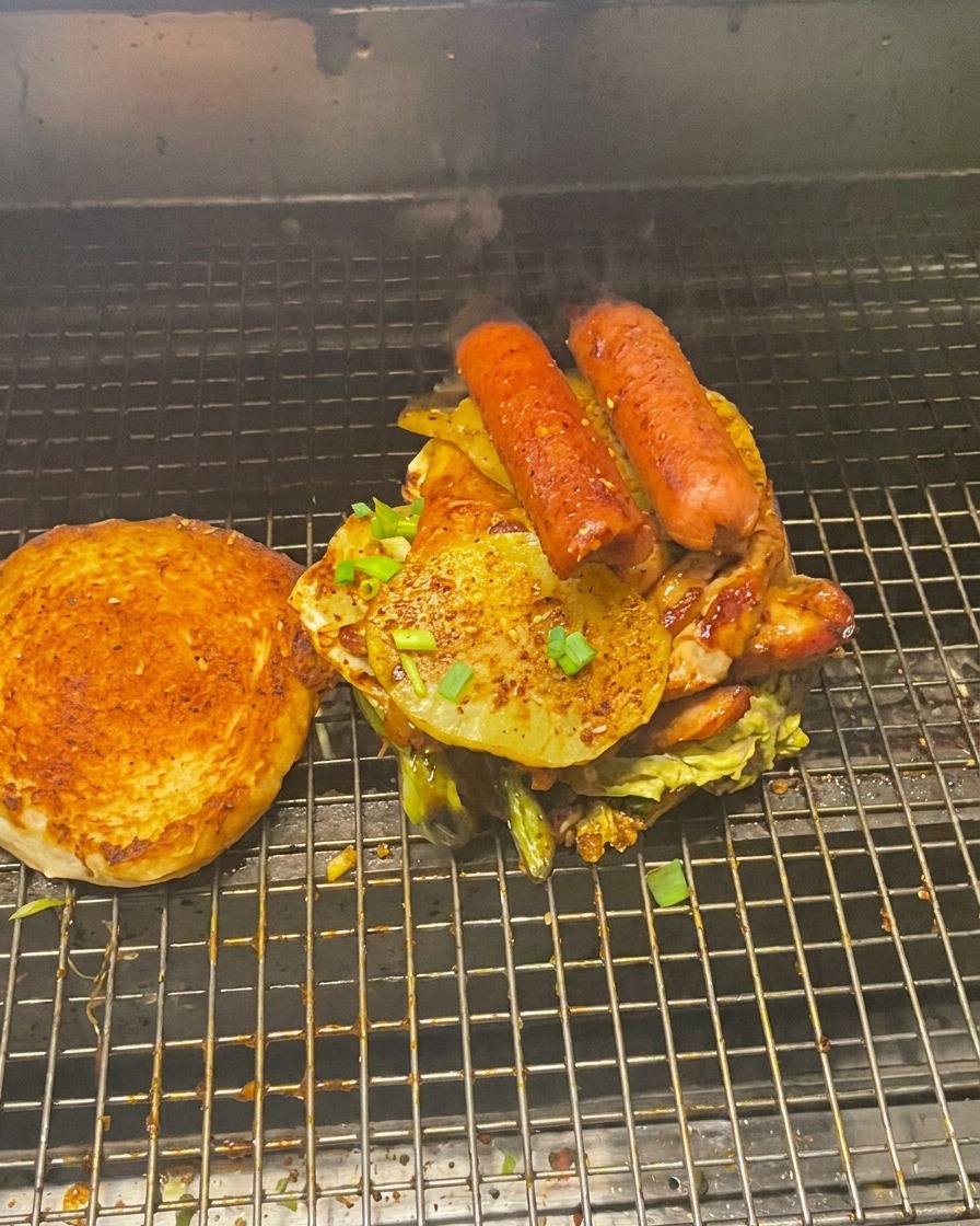 高く積み上げられた肉と野菜のタワーと、その横にあるバンズの上半分