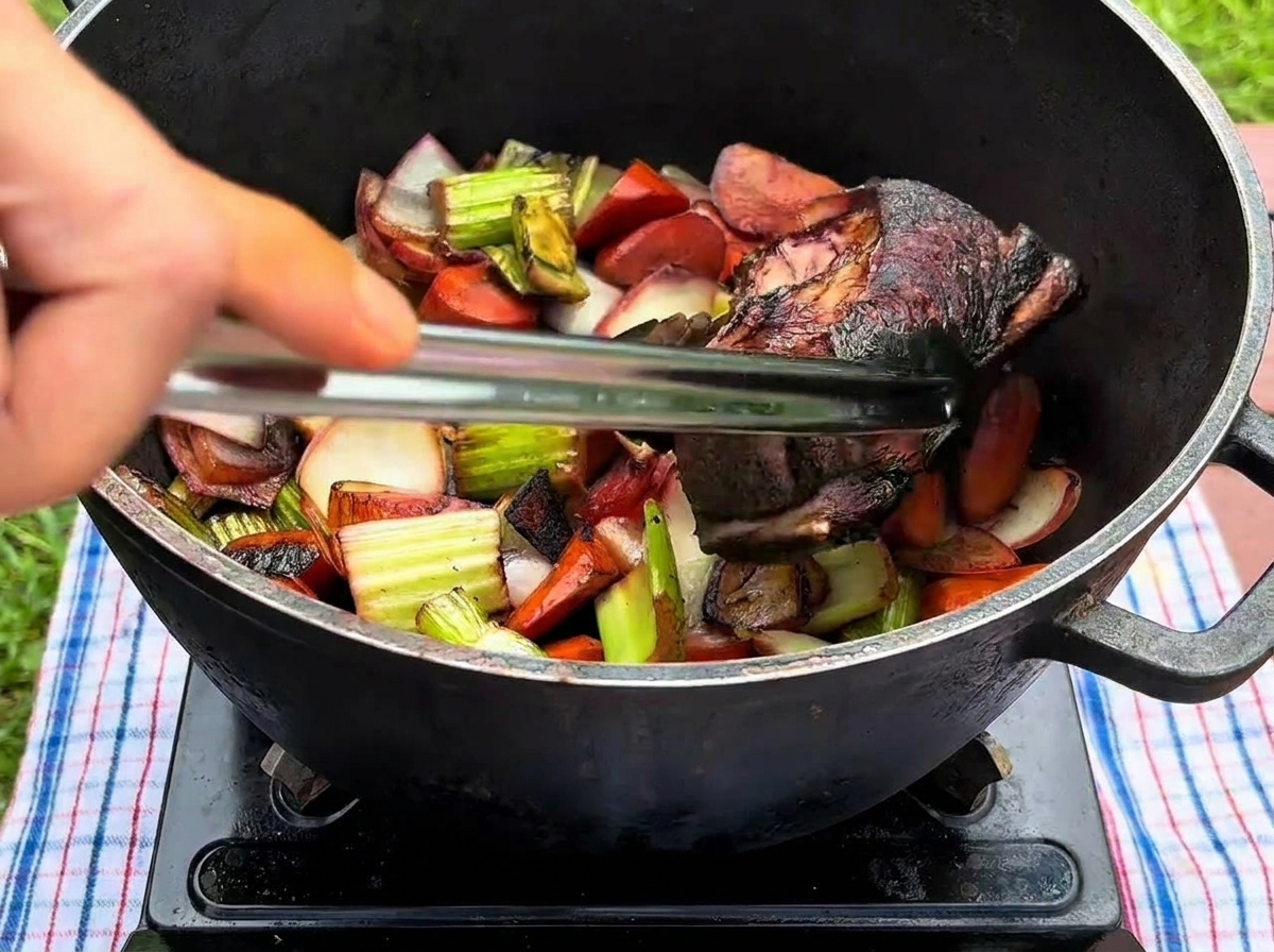 トングを使い、炒めた野菜の上にこんがり焼けた牛リブを並べている様子