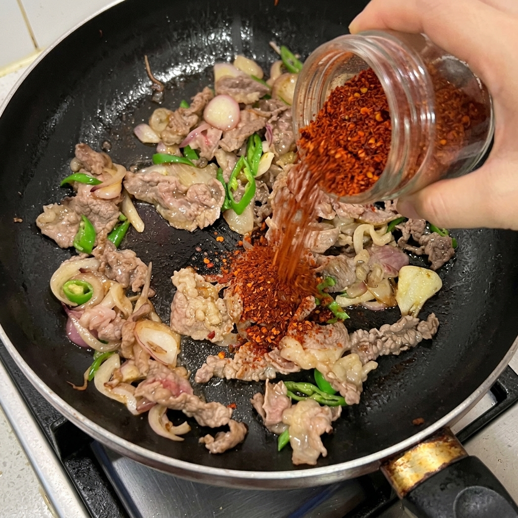 牛肉と玉ねぎにチリパウダーを振りかけて炒める様子