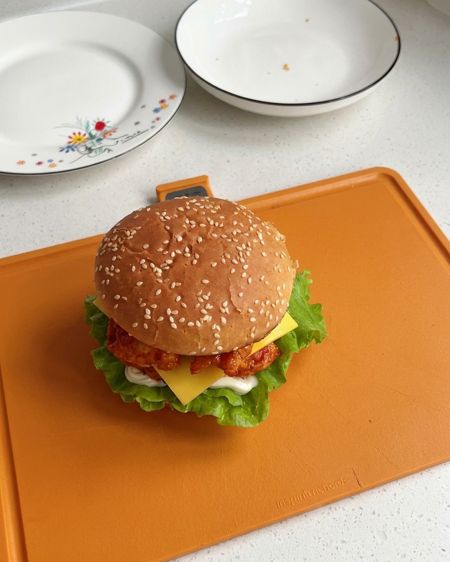 セサミバンズを冠し、レタス、チキン、とろけるチーズの層が綺麗に見える、完成したオルレアンチキンバーガー。
