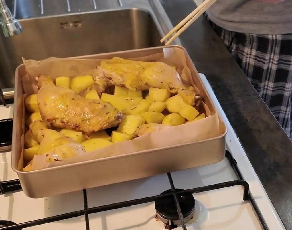 ポテトの上にのった鶏もも肉の最も厚い部分に箸を刺して、火が通っているか確認している様子。
