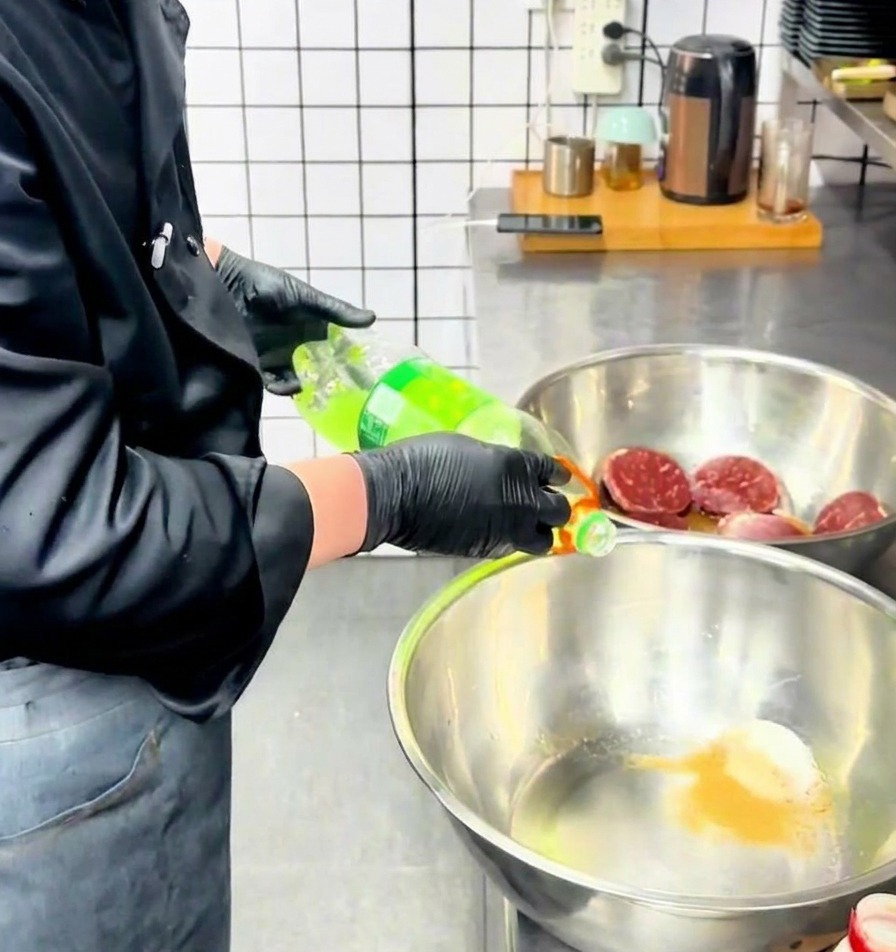 調味粉末が入ったステンレスボウルに、シェフがボトルから透明感のあるグリーンの液体を注いでいる様子。