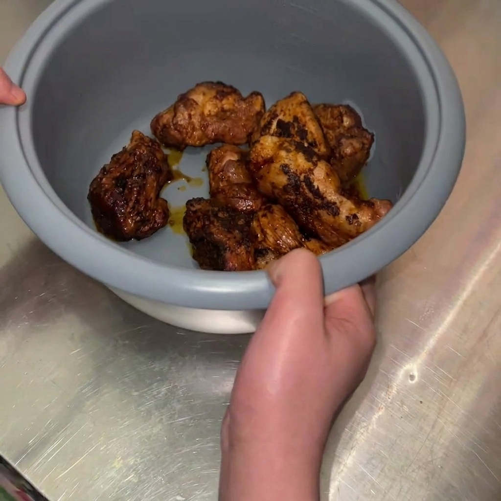 黄金色に焼けた豚肉の塊を、炊飯器の内釜に入れている様子。