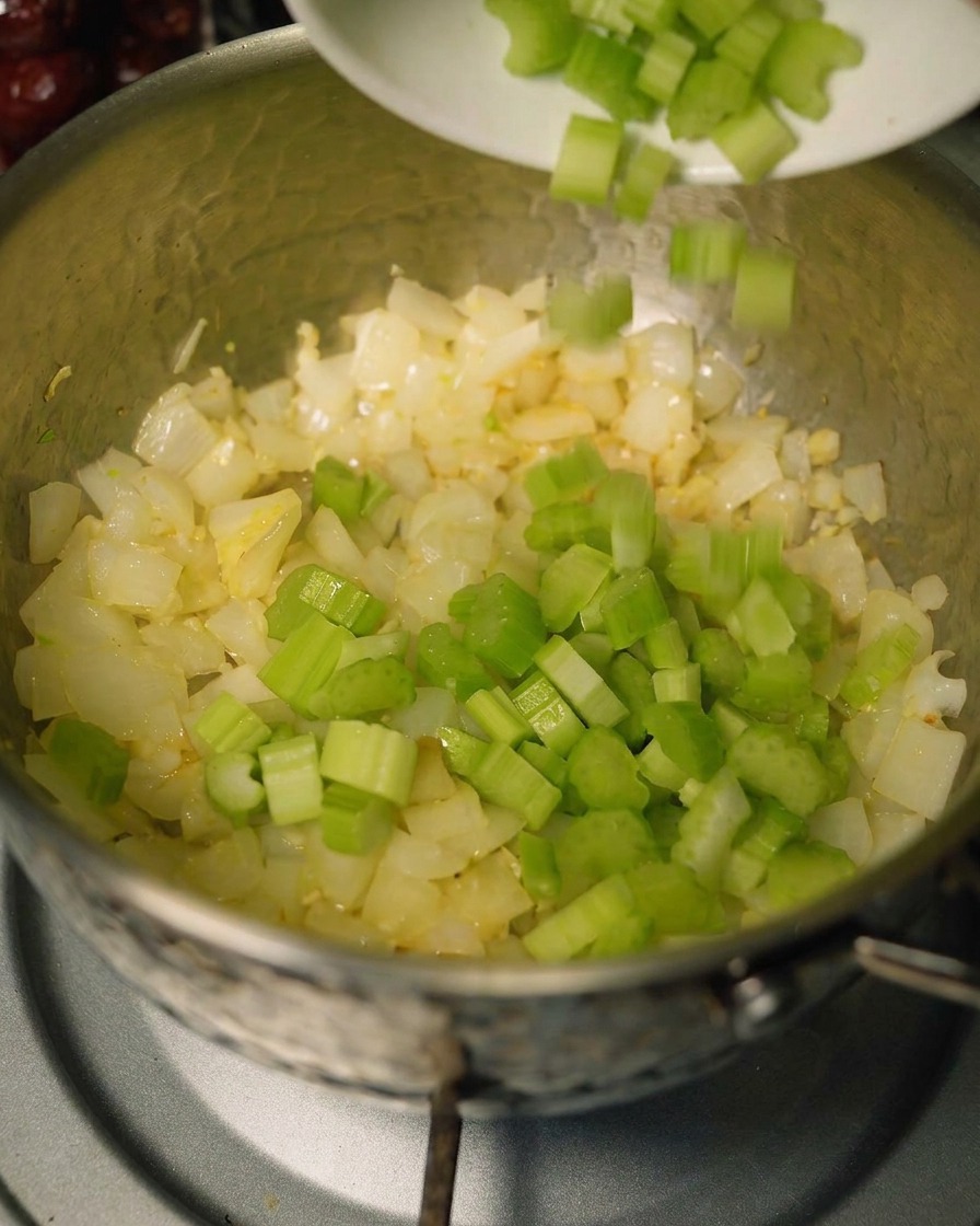 炒めた香味野菜の入った鍋に、セロリとにんじんを追加している様子。