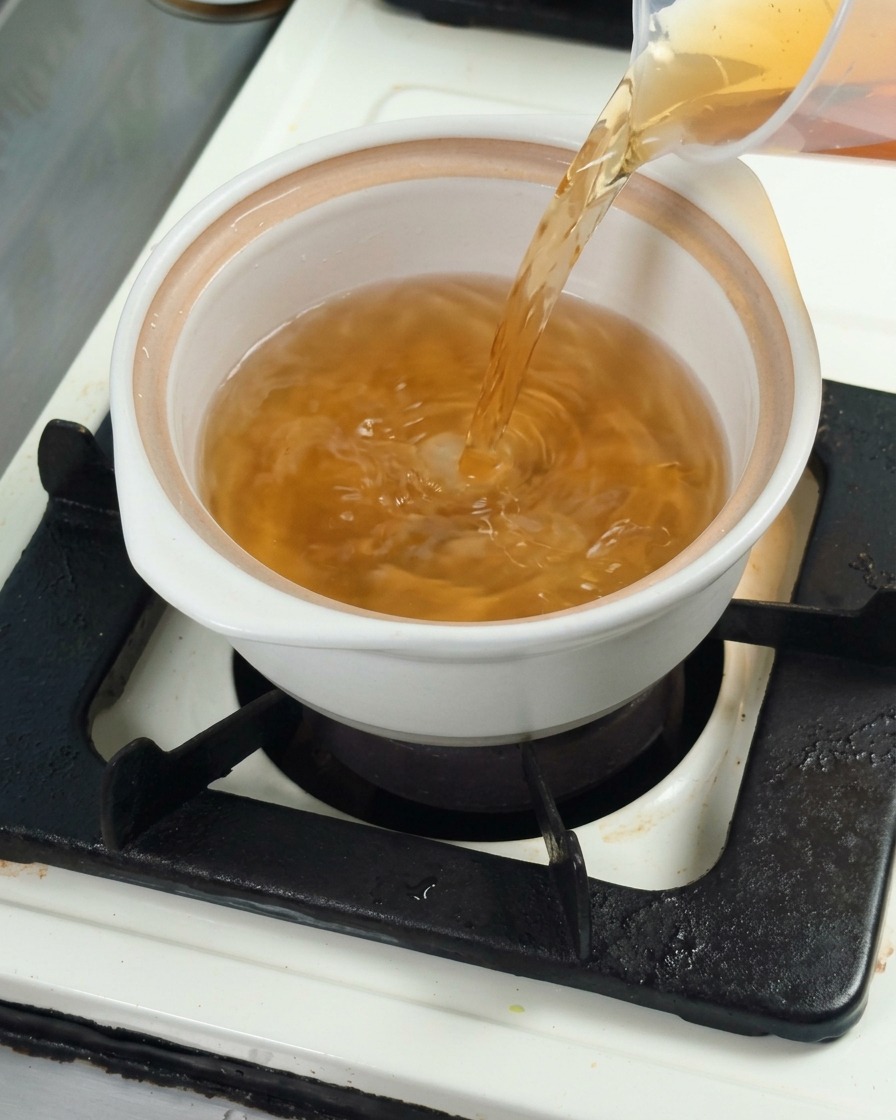 白い鍋に昆布だしを注ぎ、スープのベースを作っている様子。