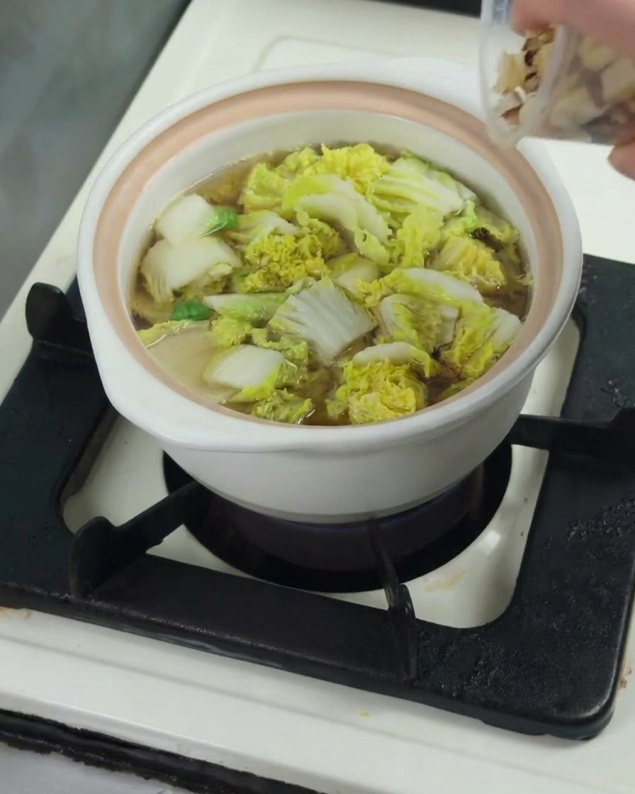 柔らかくなったチンゲン菜の入った鍋に、鶏もも肉を入れている様子。