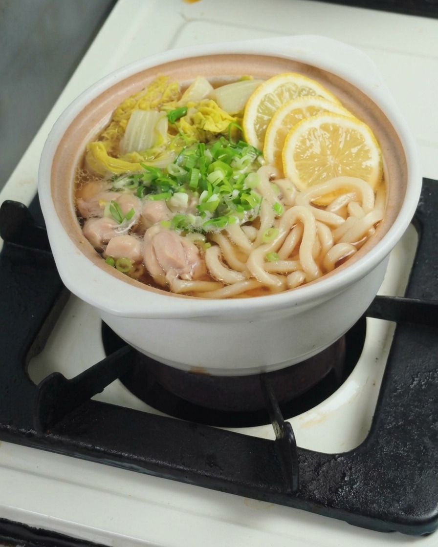 レモンを絞り、果汁をうどんの鍋に加えている様子。