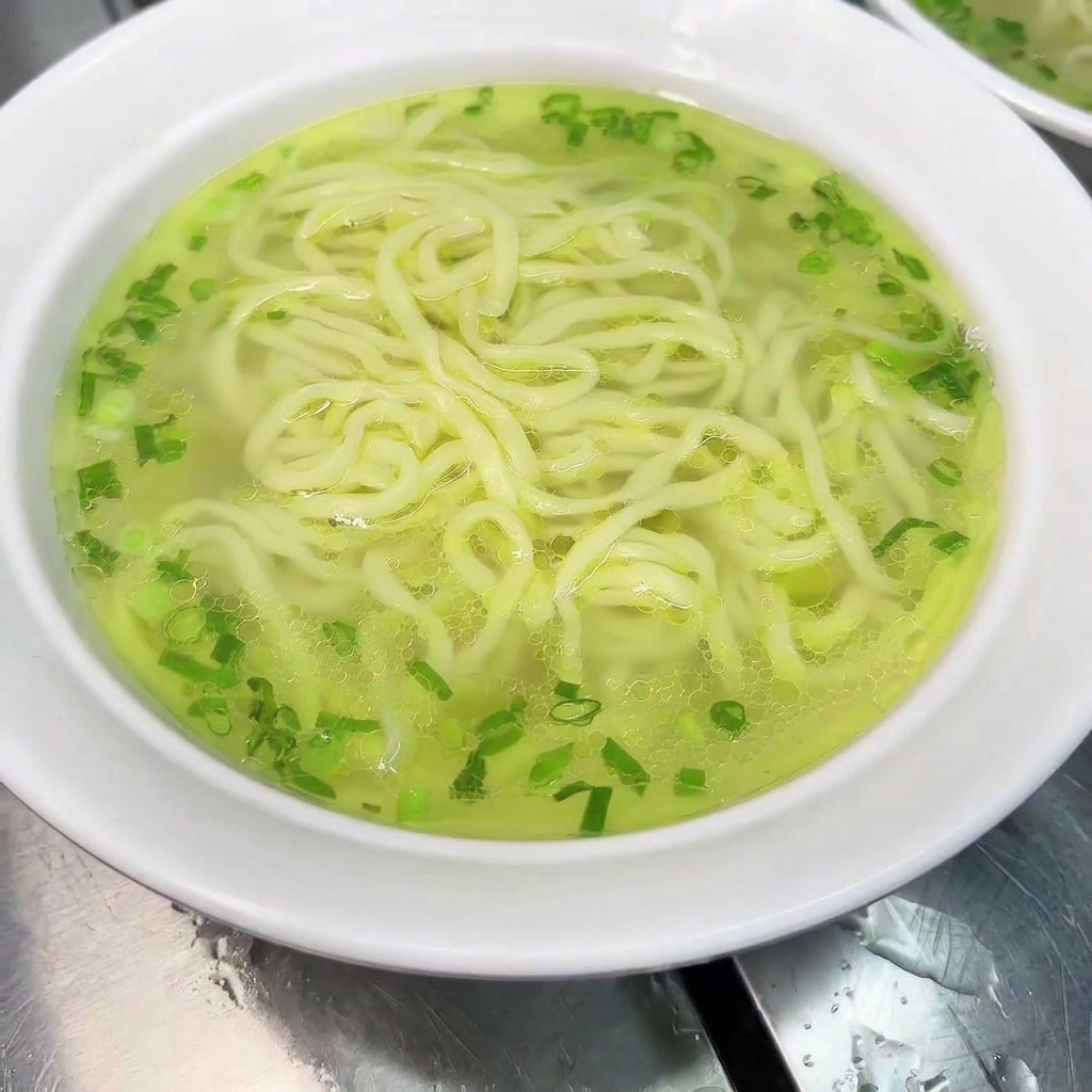 麺の上に鶏肉とスープをかけている様子