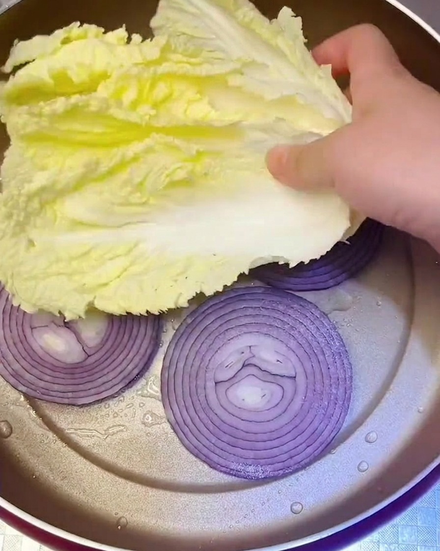 炒めた玉ねぎの上に新鮮な白菜をのせている様子。