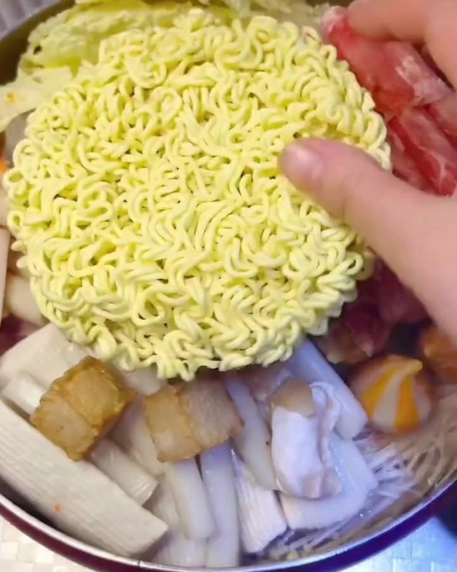 麺とスライスチーズを鍋の中央にのせて完成させる様子。