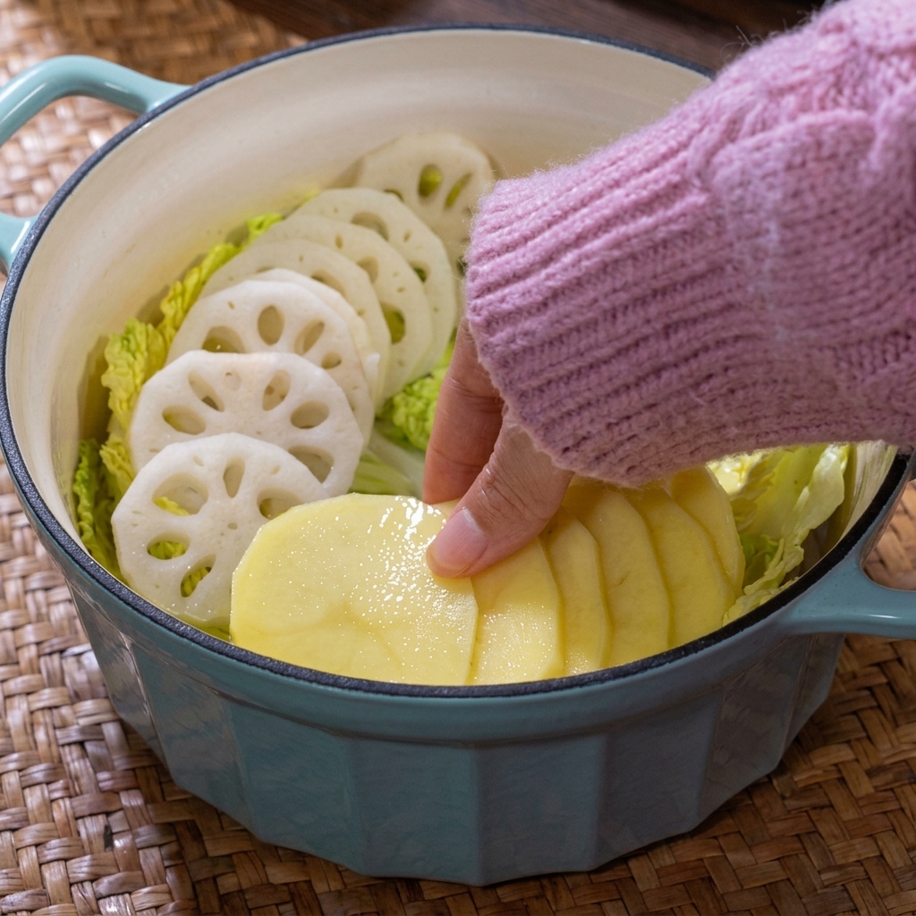 鍋の中にスライスしたじゃがいもと様々なきのこを彩りよく並べた様子。