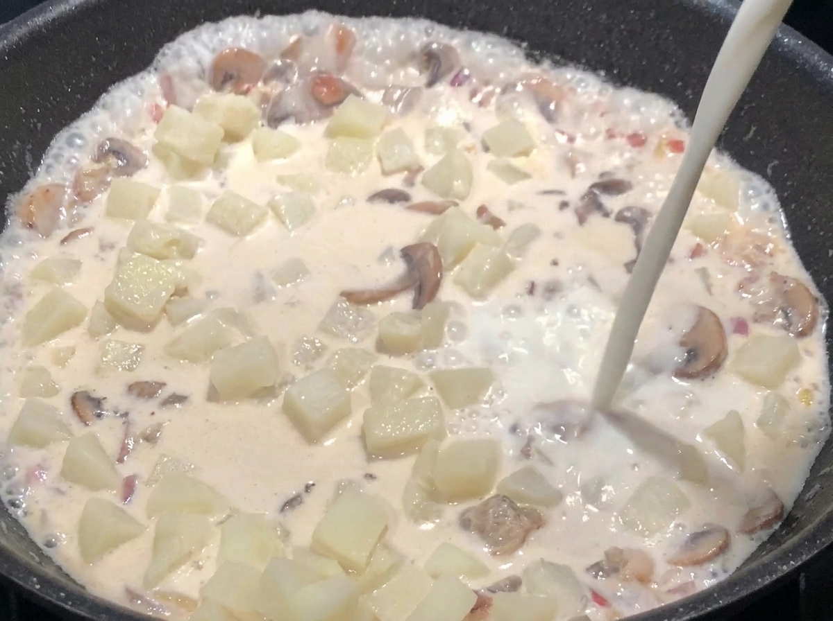 牛乳を加えて具材を浸し、とろみがつくまで煮込んでいる様子。
