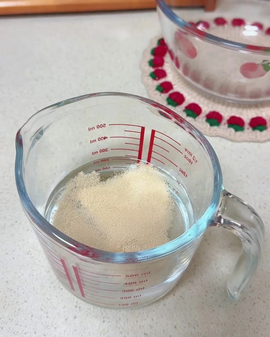 計量カップに入った水に浮かぶドライイースト。