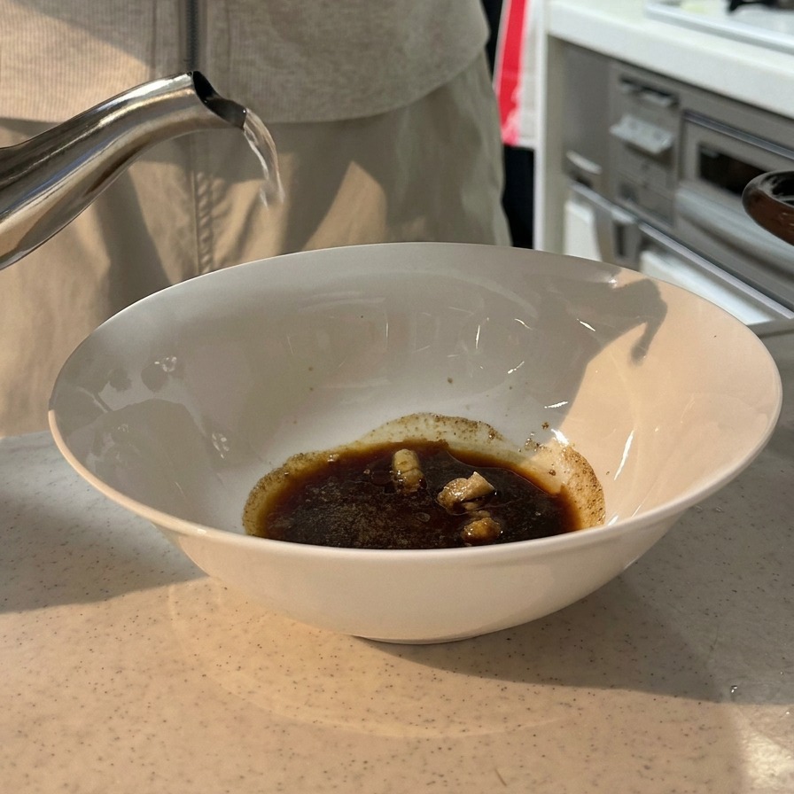 調味料を入れた丼に、ケトルから沸騰したお湯を注いでいる様子。