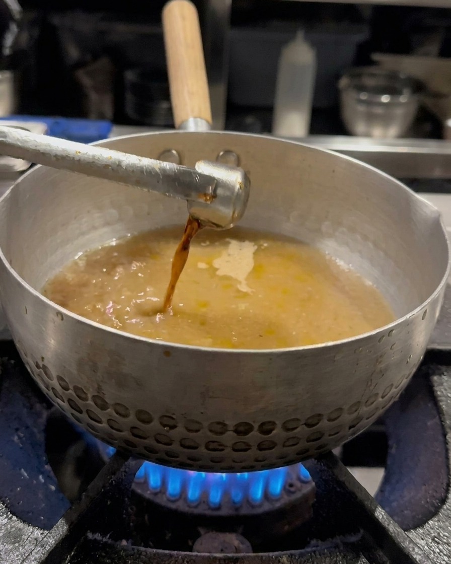 スープに醤油を加え、泡立て器で混ぜている様子。