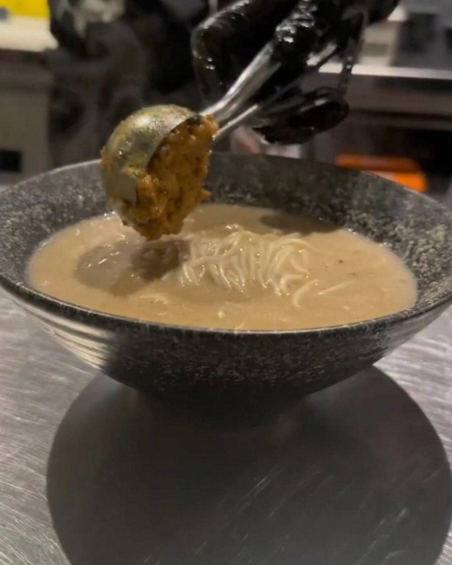 麺の上にひき肉を盛り付けている様子。