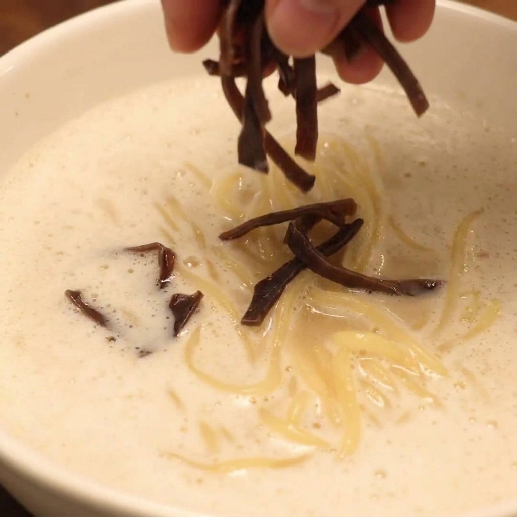 チャーシュー、きのこ、新鮮な野菜をトッピングした完成した鶏白湯泡ラーメン。