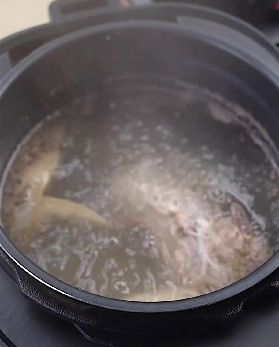 下茹でして洗った鶏の骨と足がステンレスのボウルに入っている様子