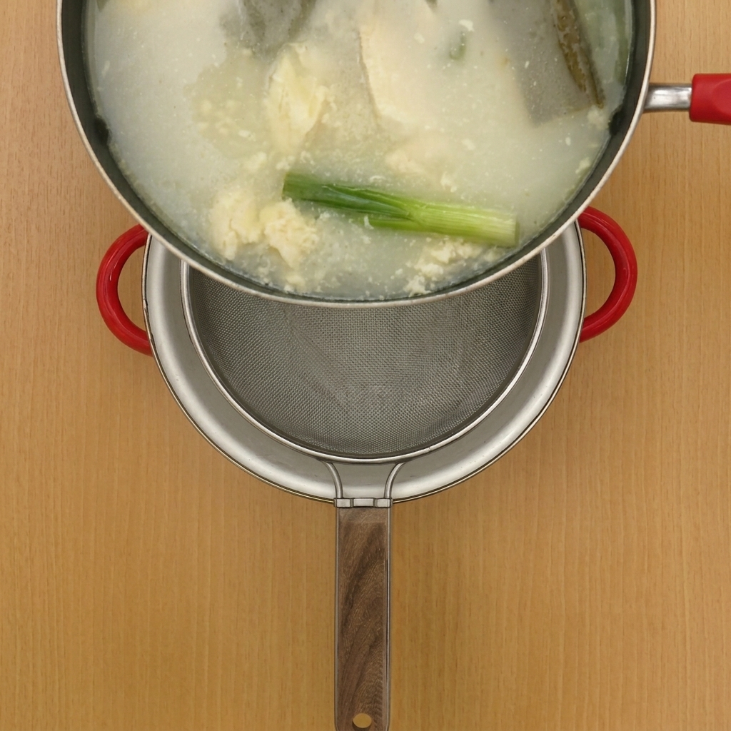 細かい網でスープを別の鍋に濾し入れている様子。