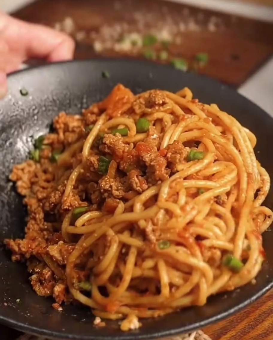茹で上がったパスタをソースの入ったフライパンに入れている様子。