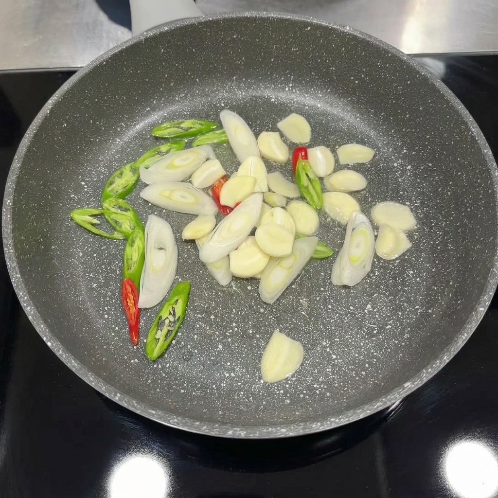 スライスしたにんにく、唐辛子、長ねぎをフライパンで香りが出るまで炒めているところ。