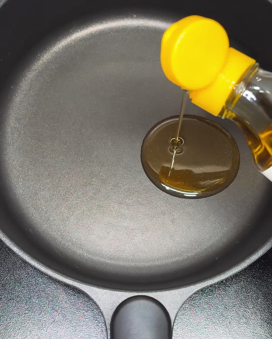 ノンスティック加工の鍋にごま油を注いでいる様子。