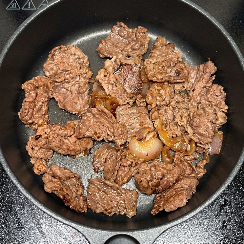 牛肉と玉ねぎが入った鍋にキムチを投入している様子。