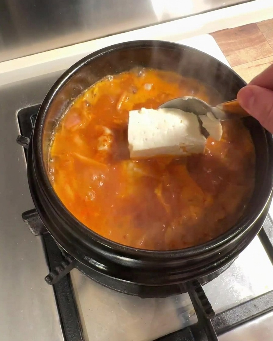 煮立ったスープの中に大きな豆腐を投入している様子。
