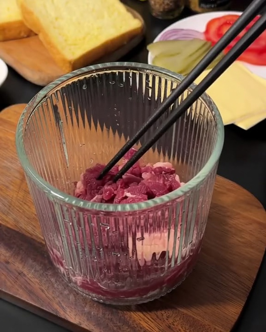 ガラス製のハンドチョッパーに入った生の牛ひき肉。