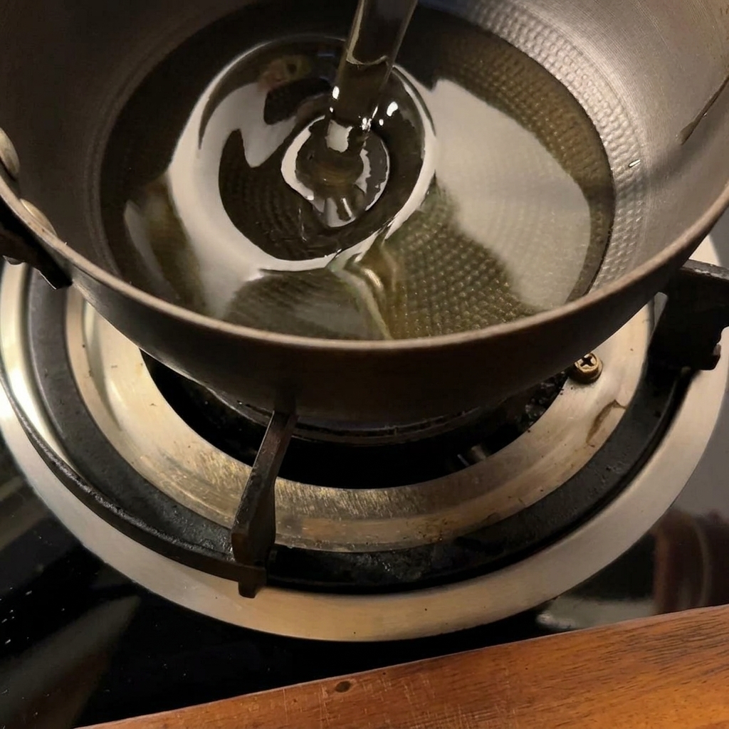 小さな鍋の油で揚げられ、きつね色になっているポテト。