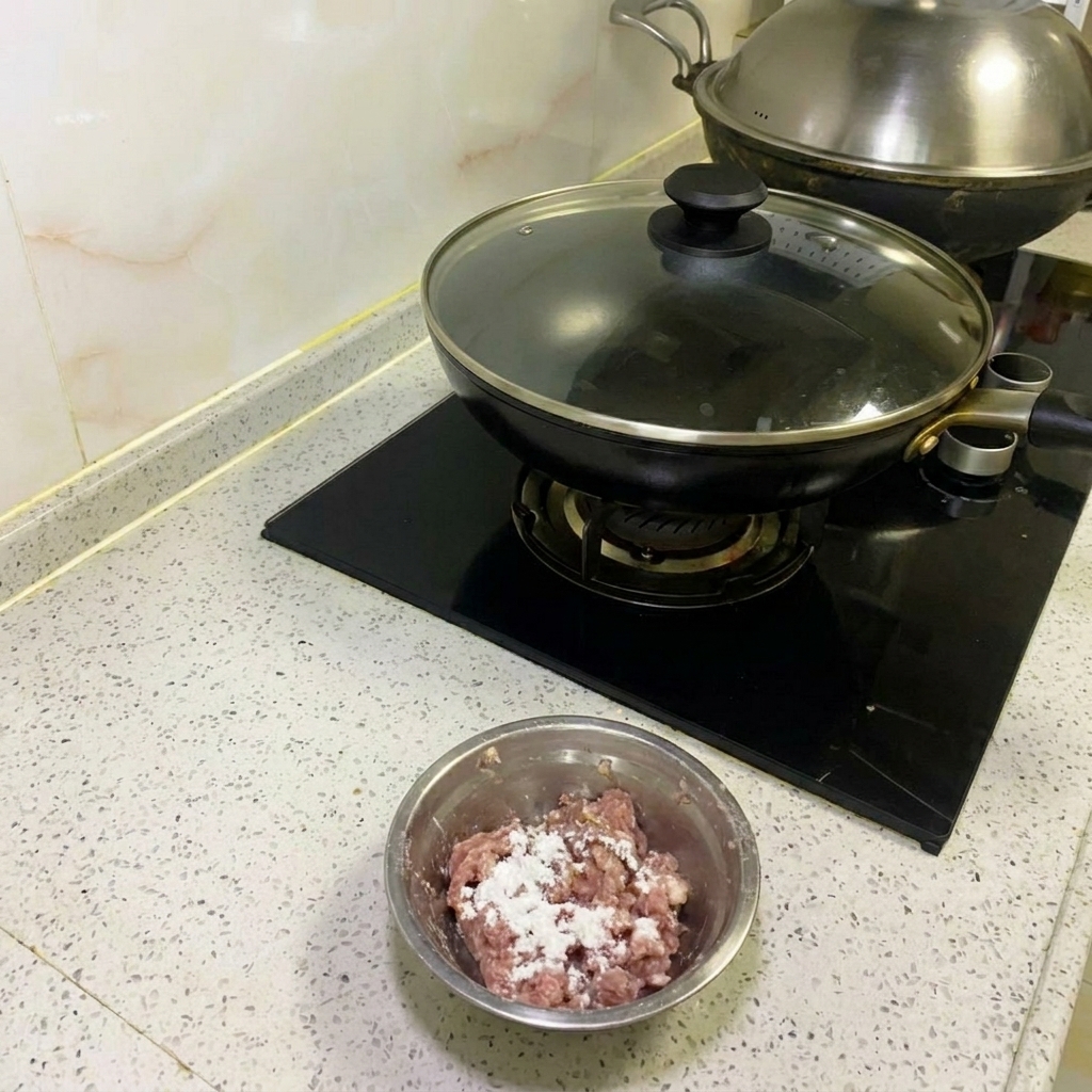 金属製の菜箸で、挽肉を粘りが出るまで一方向に混ぜている様子。