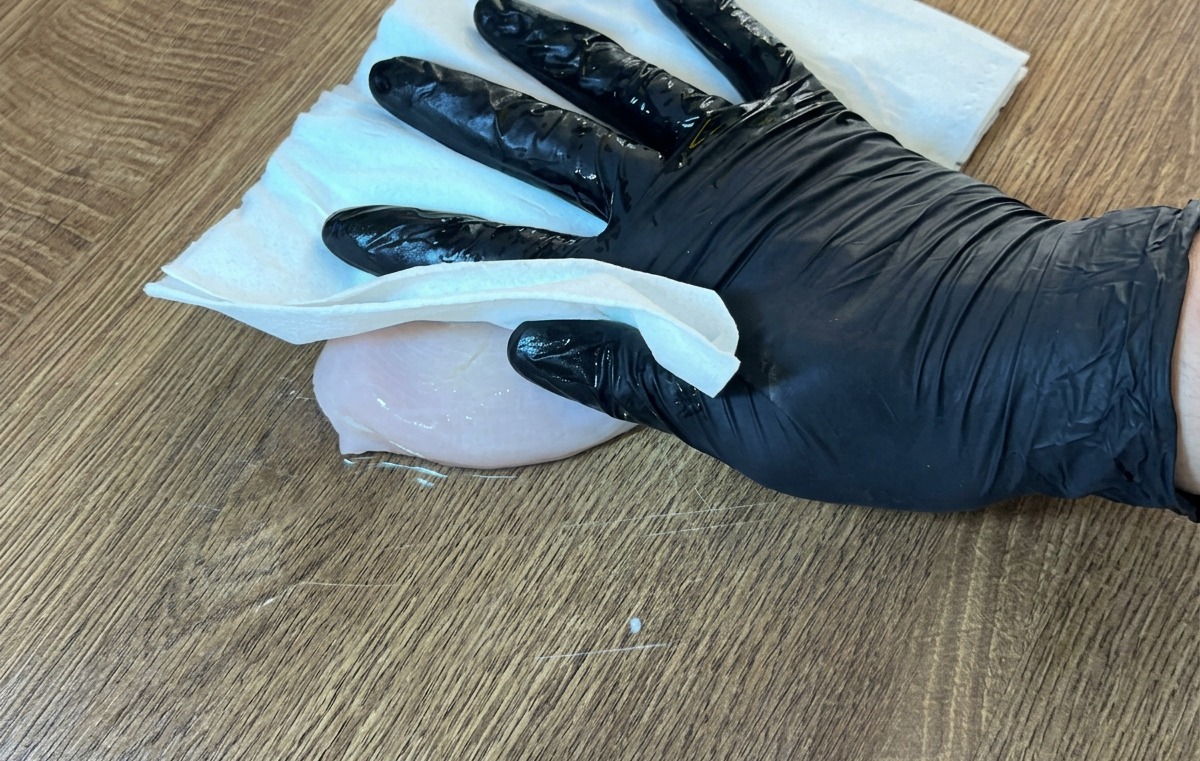 キッチンペーパーで鶏むね肉の水気を丁寧に拭き取っている様子。