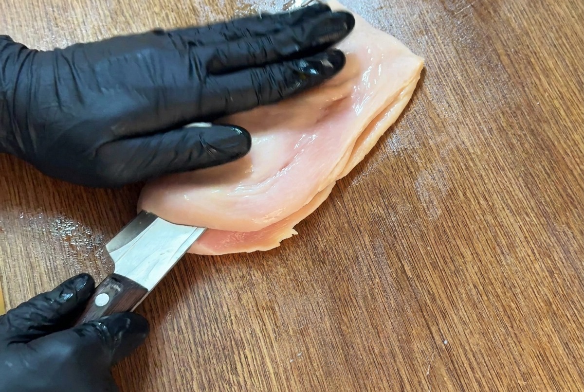 包丁で鶏むね肉を水平に切り、本のように開いている様子。