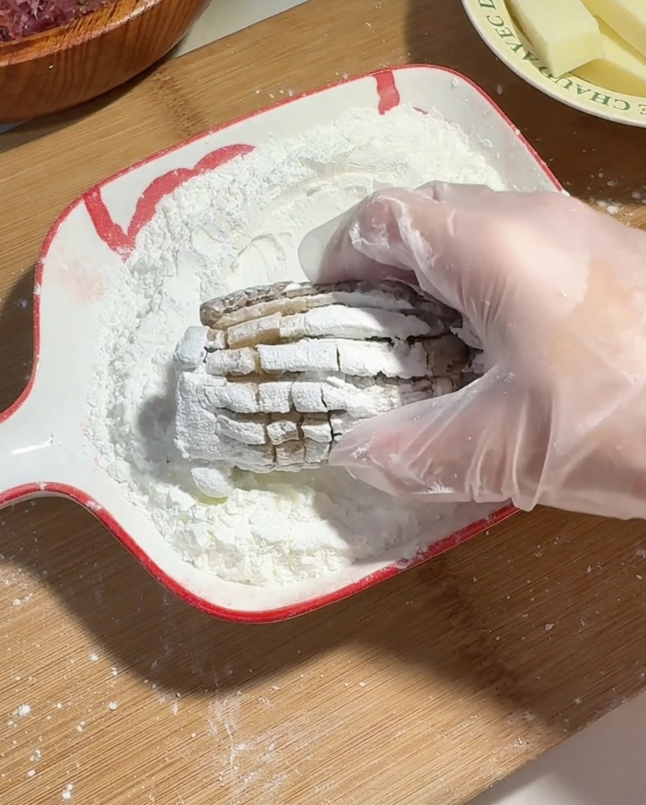 手袋をした手で、詰め物をした椎茸全体に片栗粉をまぶしている様子。