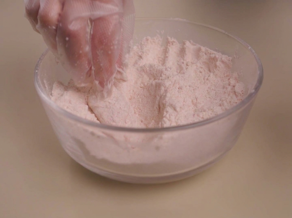 下味をつけたチキンに、スパイス粉をしっかり押し付けている様子。