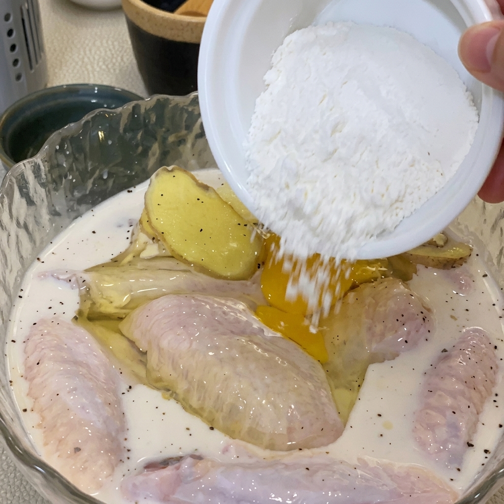 卵と小麦粉を鶏肉のボウルに加えて混ぜ合わせている様子